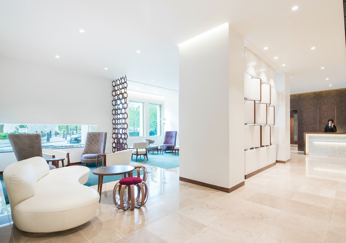 Photo of metropolitan hotel entrance lobby with bright contemporary lighting and soft seating design