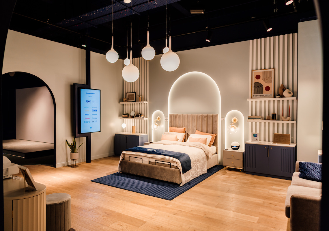 Photo of situ live retail showroom bedroom display with contemporary pendant lighting and illuminated arched niche design